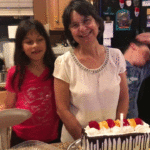 Grandmother and grandkids dancing around birthday cake